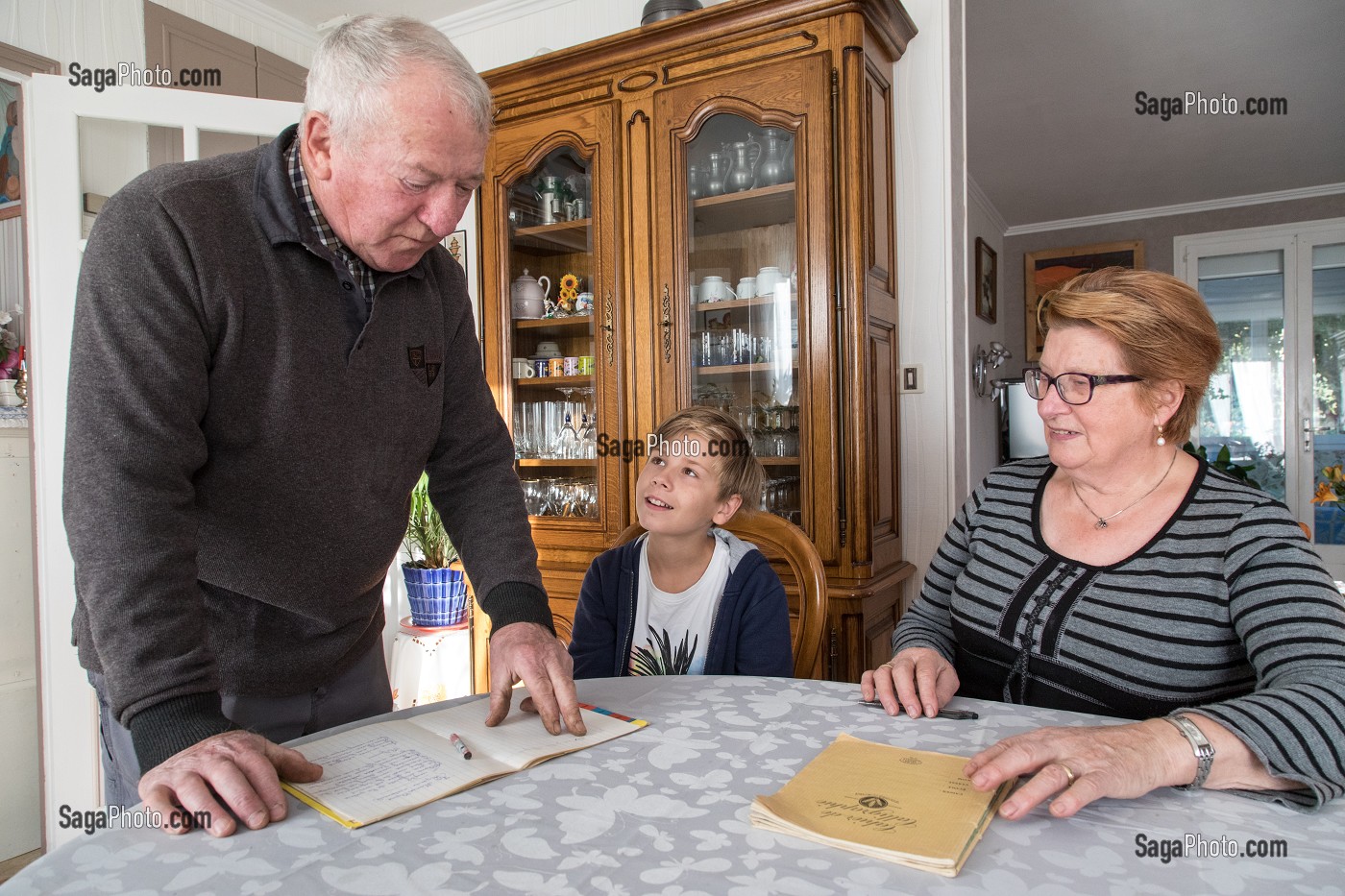 COUPLE DE PERSONNES AGEES AVEC LEUR PETIT-FILS EN TRAIN DE FAIRE LES DEVOIRS D'ECOLE LA MAISON, VILLE DE VERNEUIL-SUR-AVRE (27), FRANCE 