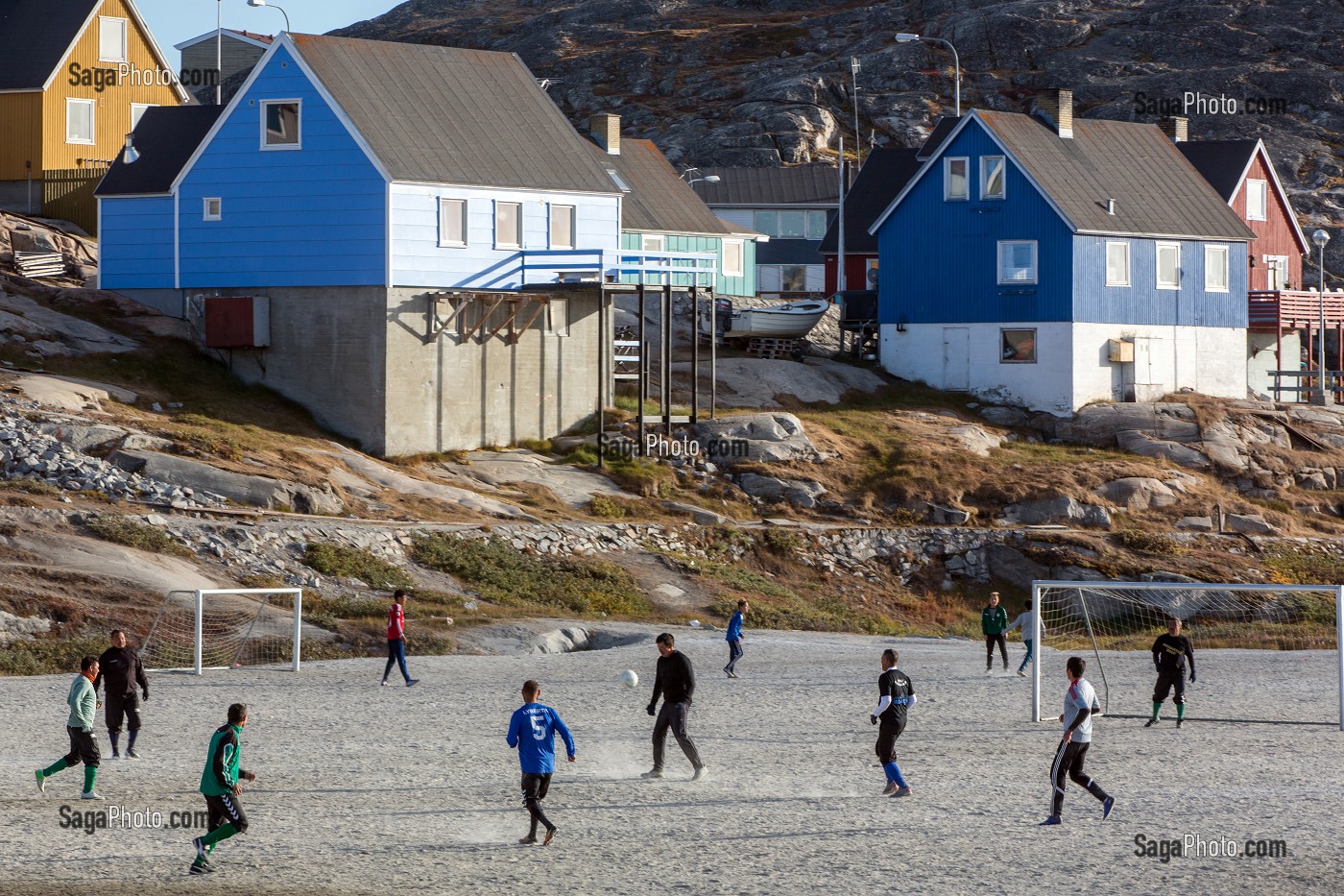 HOMMES ADULTES SUR LE TERRAIN DE FOOTBALL DEVANT LES MAISONS COLOREES, ILULISSAT, GROENLAND 