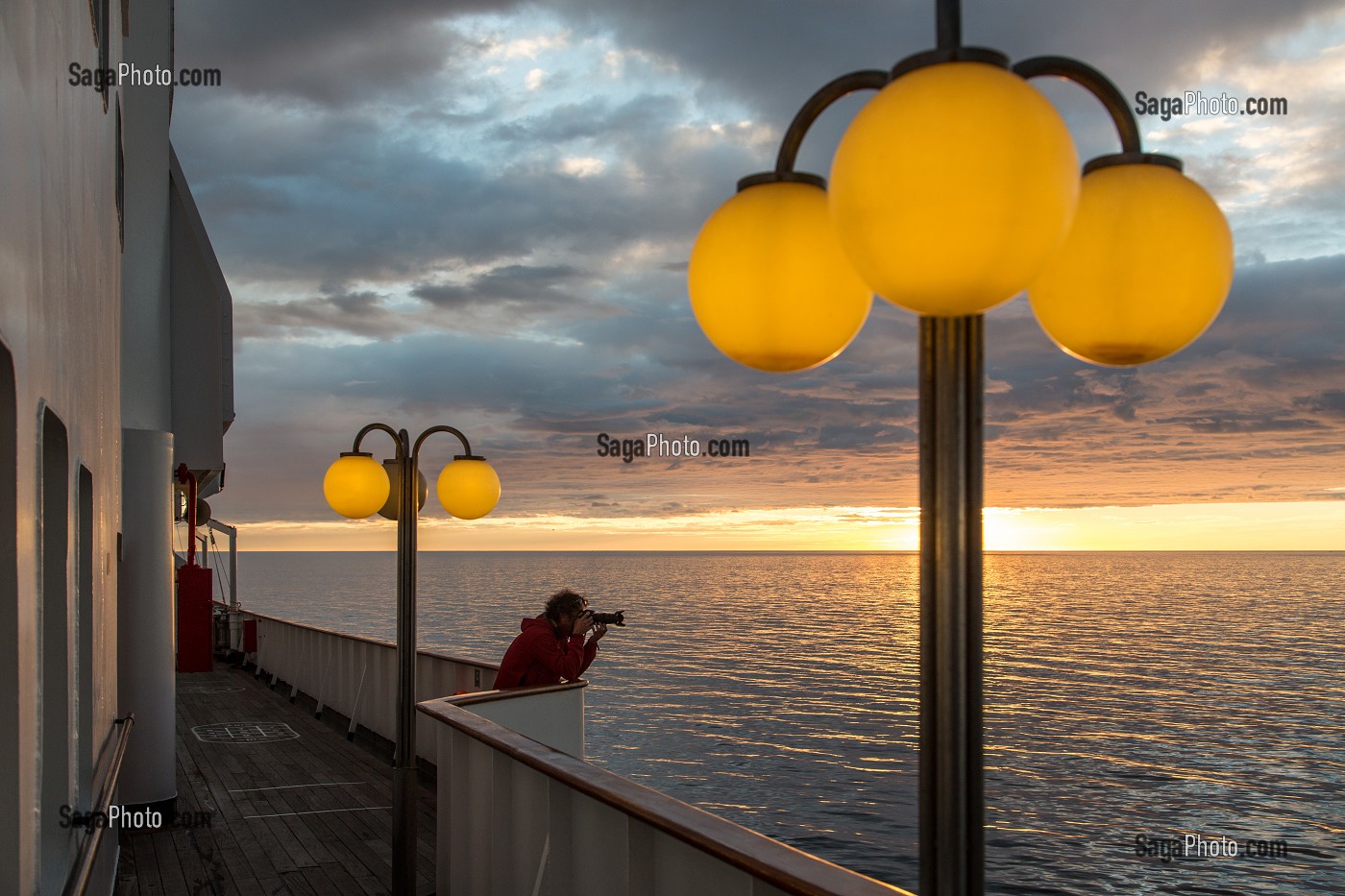 PHOTOGRAPHE DEVANT UN COUCHER DE SOLEIL SUR LE PONT SUPERIEUR DU PAQUEBOT, BATEAU DE CROISIERE ASTORIA DEVANT LES COTES ISLANDAISES, ISLANDE 