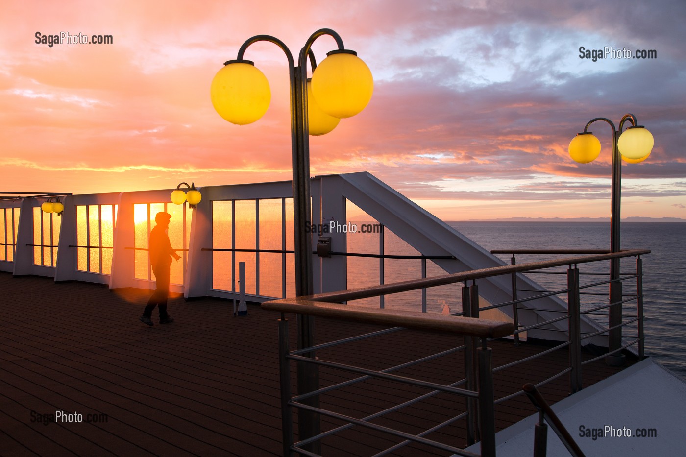 PHOTOGRAPHE DEVANT UN COUCHER DE SOLEIL SUR LE PONT SUPERIEUR DU PAQUEBOT, BATEAU DE CROISIERE ASTORIA DEVANT LES COTES ISLANDAISES, ISLANDE 