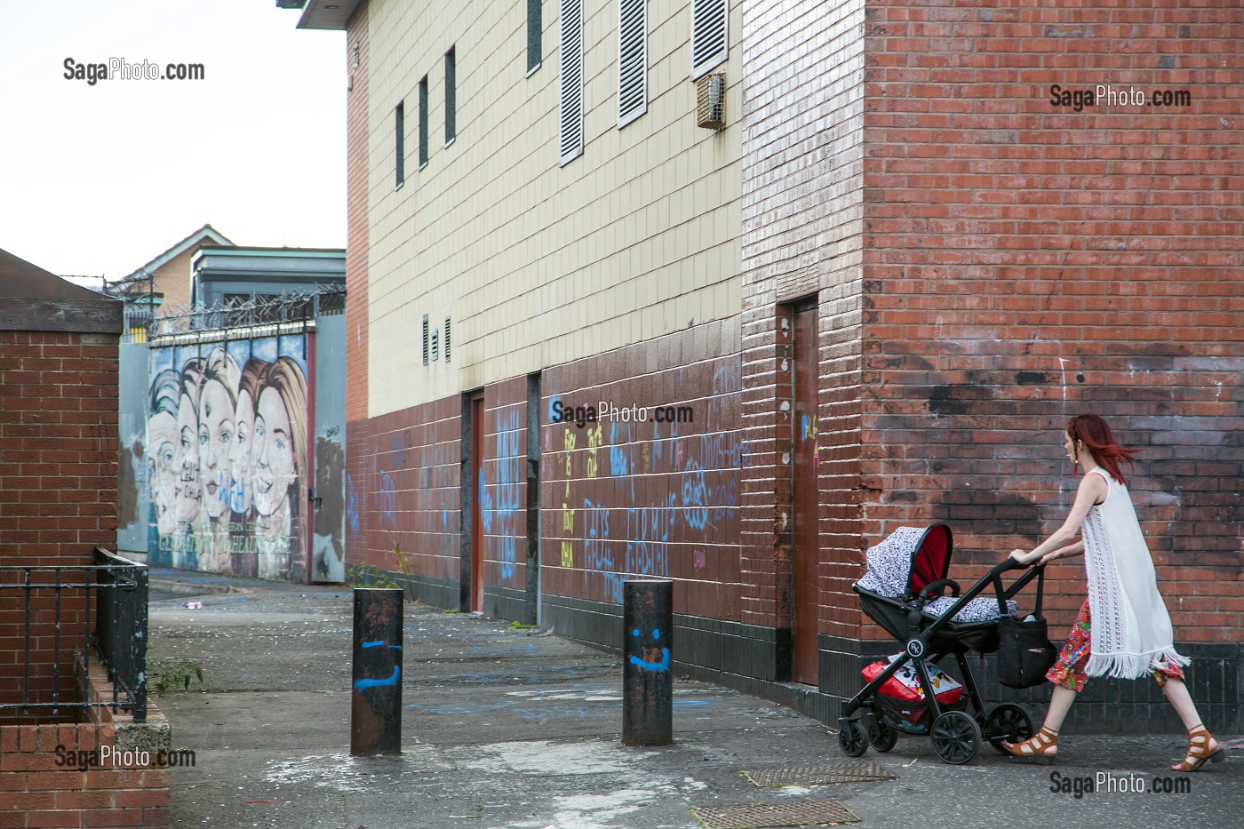 FEMME AVEC SA POUSSETTE DEVANT LES PEINTURES MURALES, QUARTIER OUEST CATHOLIQUE DE ALBERT STREET, BELFAST, ULSTER, IRLANDE DU NORD 