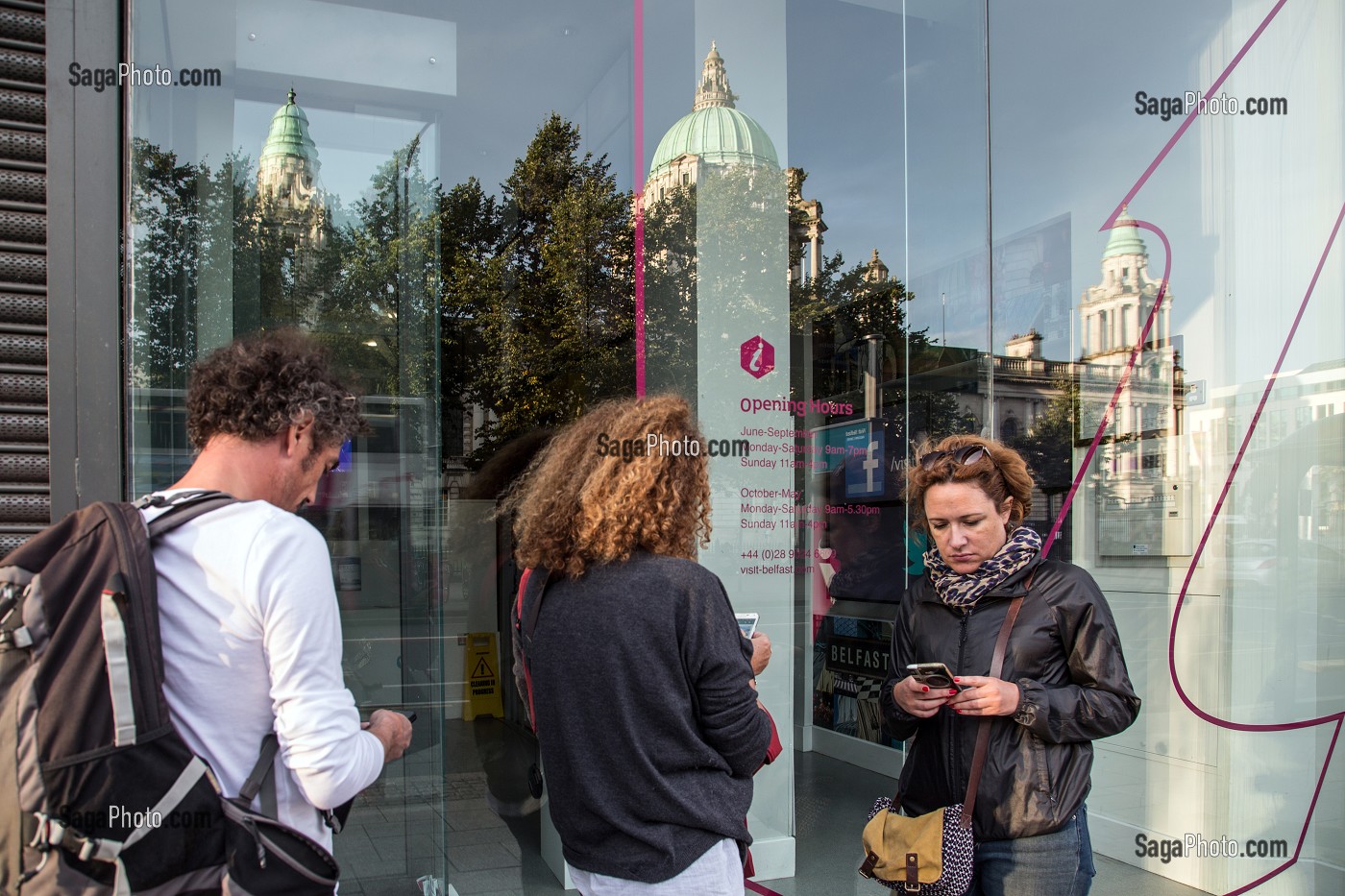 TOURISTES VOYAGEURS AVEC LEUR TELEPHONE PORTABLE POUR CAPTER LE WIFI DE L'OFFICE DE TOURISME DEVANT LE BELFAST CITY HALL, DONEGALL SQUARE, BELFAST, ULSTER, IRLANDE DU NORD 