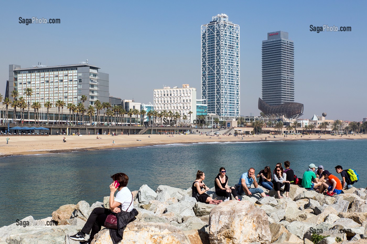 GROUPE DE JEUNES SUR LES ROCHERS AU BORD DE LA PLAGE, PASSEIG MARITIM DE LA BARCELONETA, BARCELONE, CATALOGNE, ESPAGNE 