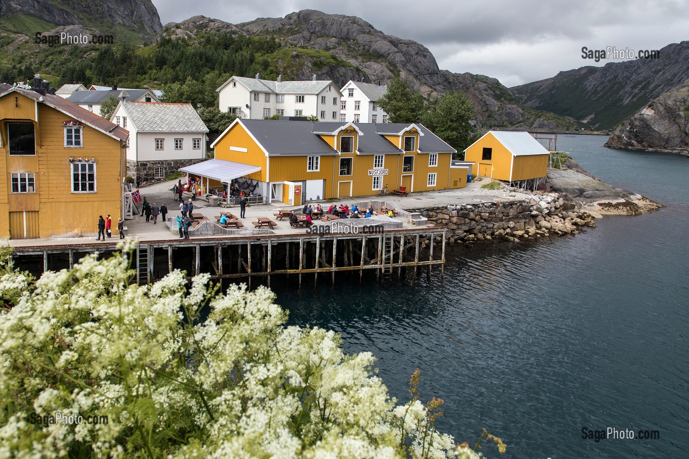 PORT DE PECHE ENTOURE DE MONTAGNE AVEC SES MAISONS DE PECHEURS TRADITIONNELLES EN BOIS DE COULEUR JAUNE, NUSFJORD, FJORD DE VESTFJORD, ILES LOFOTEN, NORVEGE 