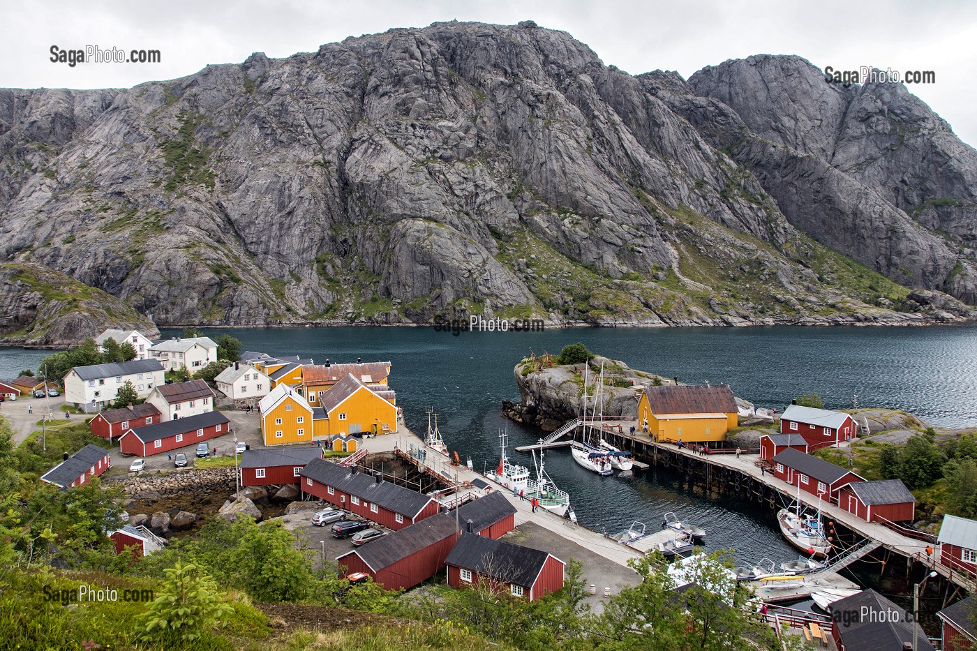 PORT DE PECHE ENTOURE DE MONTAGNE AVEC SES MAISONS DE PECHEURS TRADITIONNELLES EN BOIS DE COULEUR ROUGE ET JAUNE, NUSFJORD, FJORD DE VESTFJORD, ILES LOFOTEN, NORVEGE 