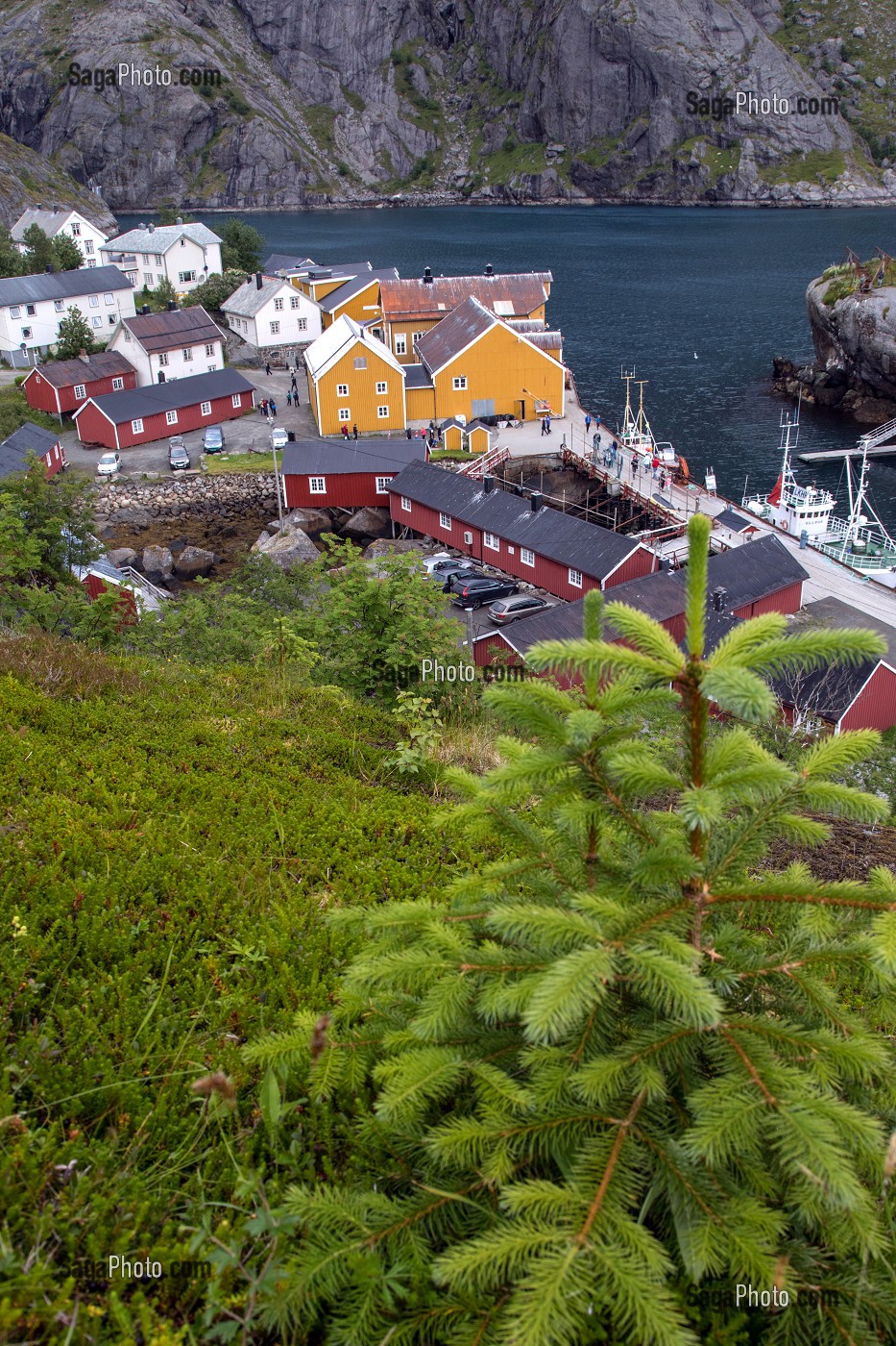 PORT DE PECHE ENTOURE DE MONTAGNE AVEC SES MAISONS DE PECHEURS TRADITIONNELLES EN BOIS DE COULEUR ROUGE ET JAUNE, NUSFJORD, FJORD DE VESTFJORD, ILES LOFOTEN, NORVEGE 