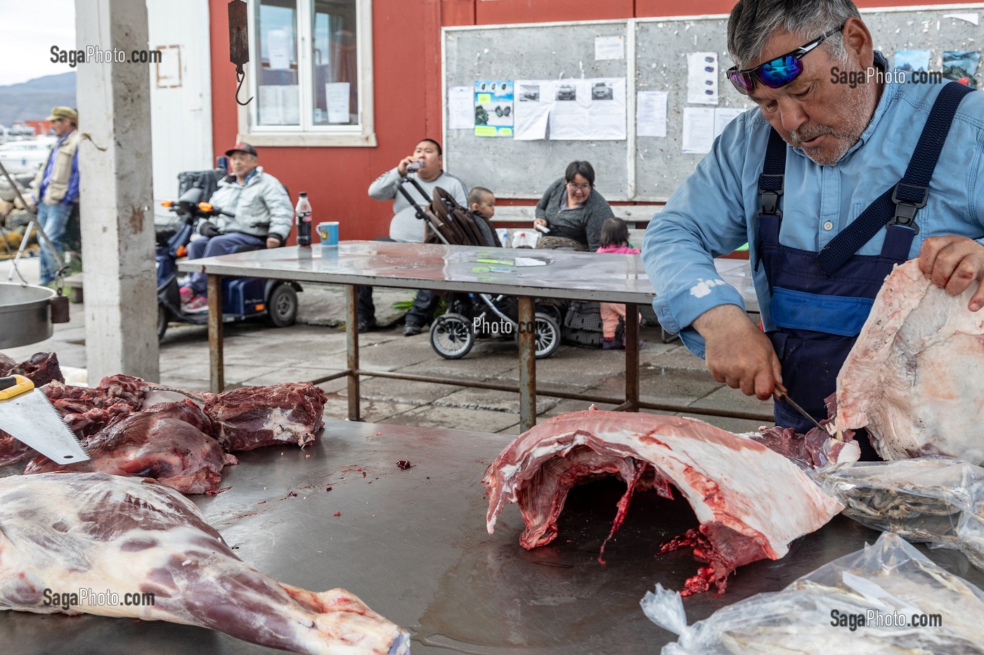 BOUCHER DECOUPANT DES CARCASSES DE BOEUF MUSQUE AU MARCHE AU VIANDE, VILLE DE QAQORTOQ, GROENLAND, DANEMARK 