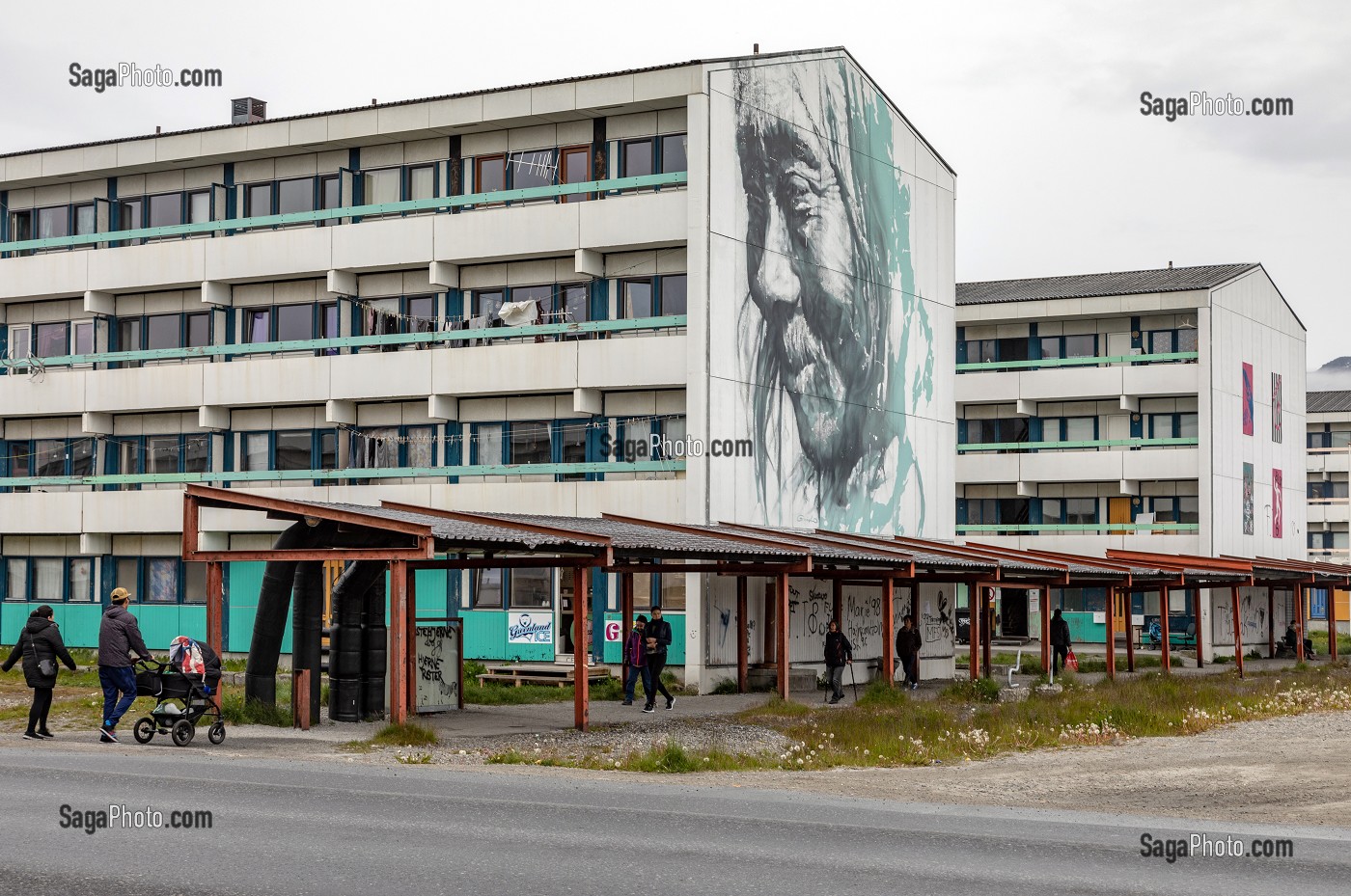 HABITANTS SE PROMENANT DEVANT UNE CITE HLM PEINTE AVEC LE PORTRAIT D'UN INUIT, NUUK, GROENLAND, DANEMARK 