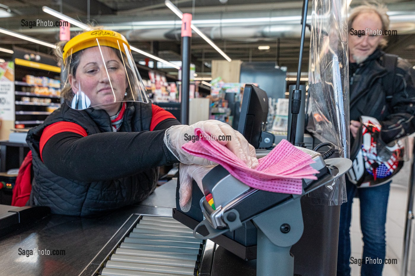 NETTOYAGE DE CAISSE ET TERMINAL DE CARTE BANCAIRE APRES CHAQUE CLIENT, CAISSIERE AU SUPERMACHE AVEC SON MASQUE DE PROTECTION ET SES GANTS, MESURES SANITAIRES DE PREVENTION, EPIDEMIE DE CORONAVIRUS, INTERMARCHE, RUGLES, NORMANDY, FRANCE 