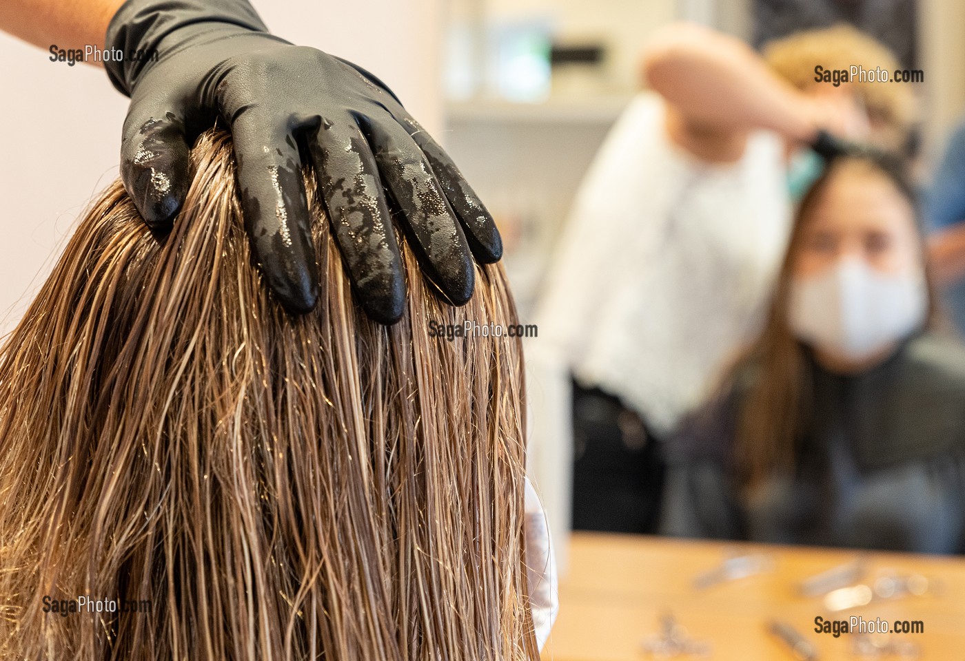 MAIN GANTEE DE LA COIFFEUSE SUR LES CHEVEUX D'UNE CLIENTE DANS LE SALON DE COIFFURE VIDE, RUGLES, NORMANDIE, FRANCE 