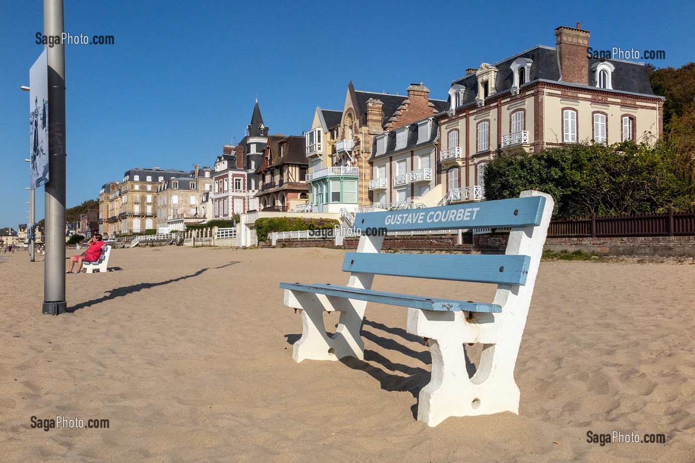 BANC PEINT EN BLANC POUR GUSTAVE COURBET SUR LA PLAGE DEVANT LES IMMEUBLES ANCIENS DU DEBUT XX EME SIECLE, TROUVILLE-SUR-MER, NORMANDIE, FRANCE 