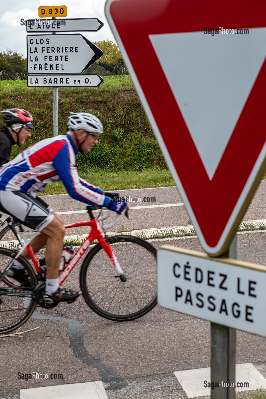 CYCLISTES SUR UNE ROUTE DEPARTEMENTALE D830 INDIQUANT LES PROCHAINS VILLAGES, CEDEZ LE PASSAGE, RUGLES, EURE, NORMANDIE, FRANCE 