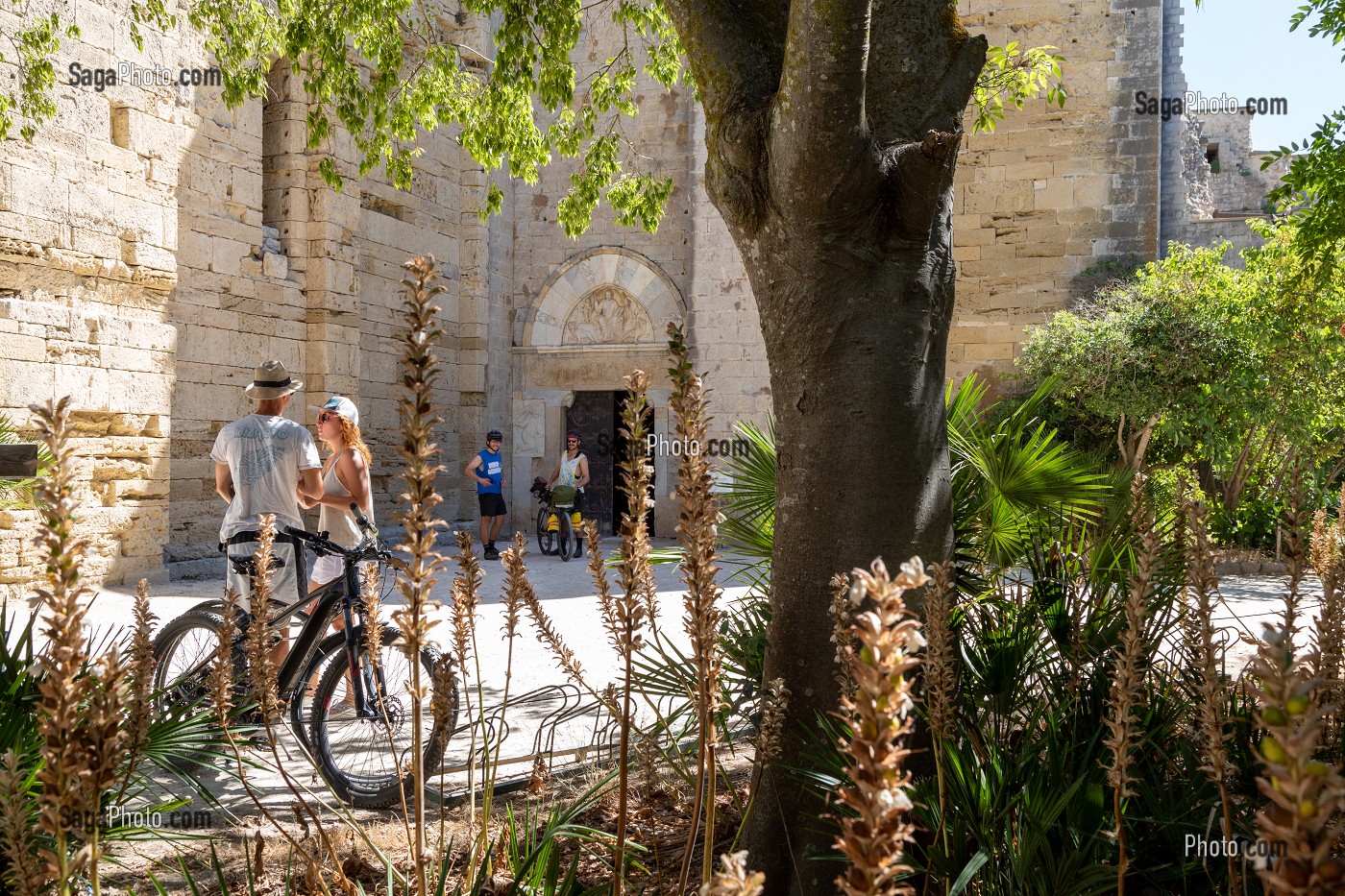 COUPLE A VELO DEVANT L'ENTREE DE LA CATHEDRALE DE MAGUELONE, EGLISE INSULAIRE RESTAUREE, VILLENEUVE-LES MAGUELONE, HERAULT, OCCITANIE, FRANCE 