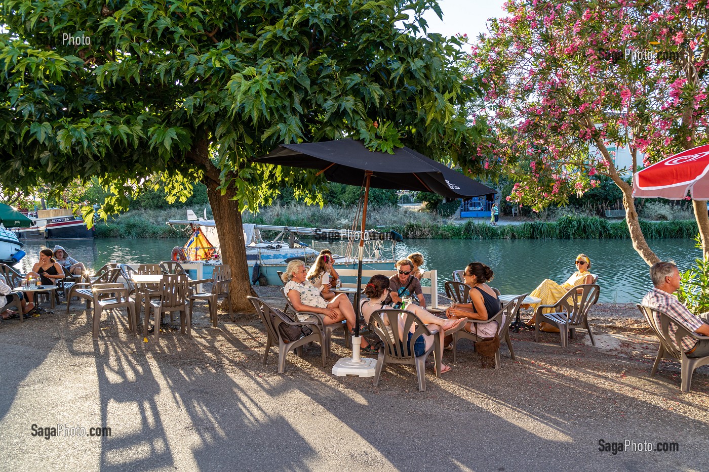 CLIENTS A LA TERRASSE SUR PORT FLUVIAL DE HOMPS, CANAL DU MIDI, AUDE, OCCITANIE, FRANCE 