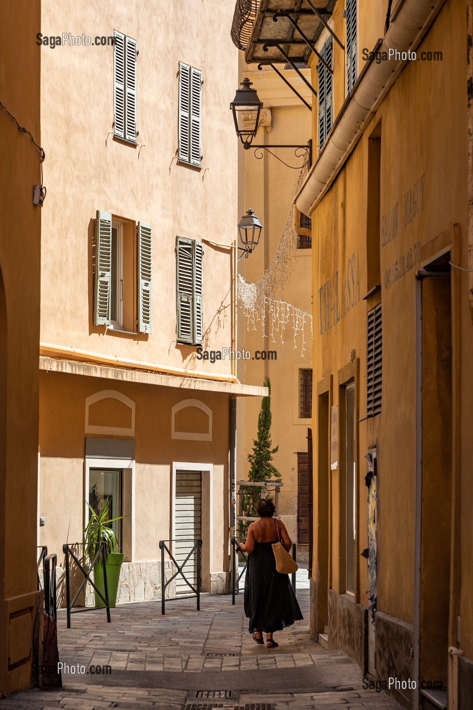 FEMME MARCHANT DANS UNE RUELLE OCRE A BASTIA