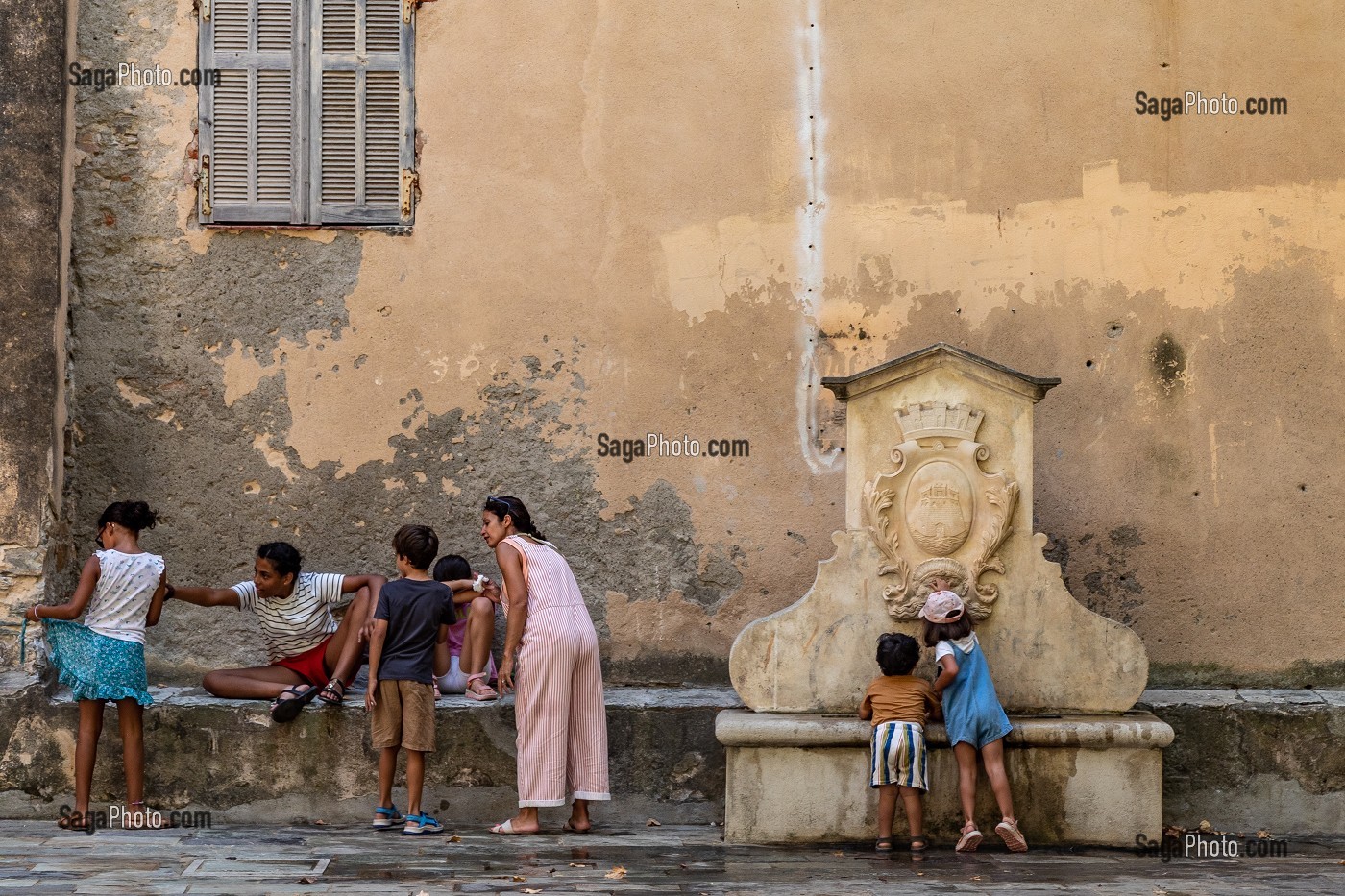 FAMILLE ET ENFANTS PRES D'UNE FONTAINE EN PIERRE SUR LA PLACE GUASCO A BASTIA