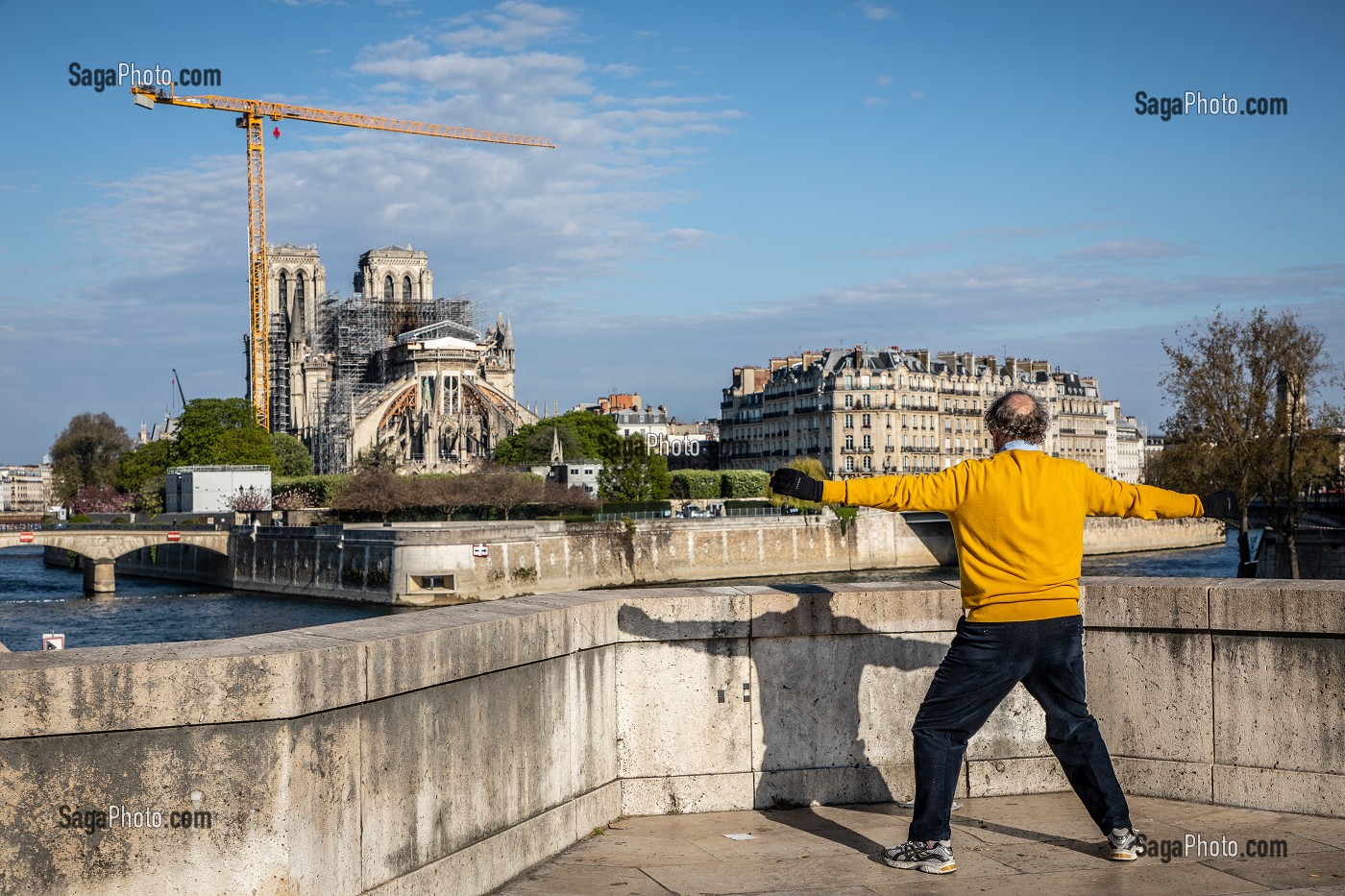 SENIOR FAISANT DE LA GYMNASTIQUE DEVANT LE CHANTIER DE RECONSTRUCTION DE NOTRE DAME DE PARIS A L'ARRET LORS DU CONFINEMENT DE LA PANDEMIE DU COVID 19, PONT DE LA TOURNELLE, PARIS, ILE DE FRANCE 