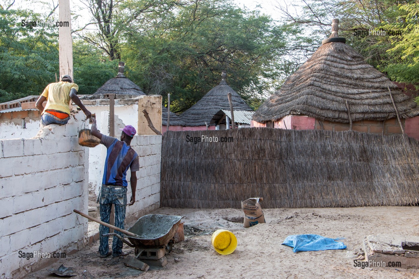 CONSTRUCTION D'UN MUR DEVANT LES CASES AU TOIT DE PAILLE, VILLAGE PEUL DE GUELAKH, SENEGAL, AFRIQUE DE L'OUEST 