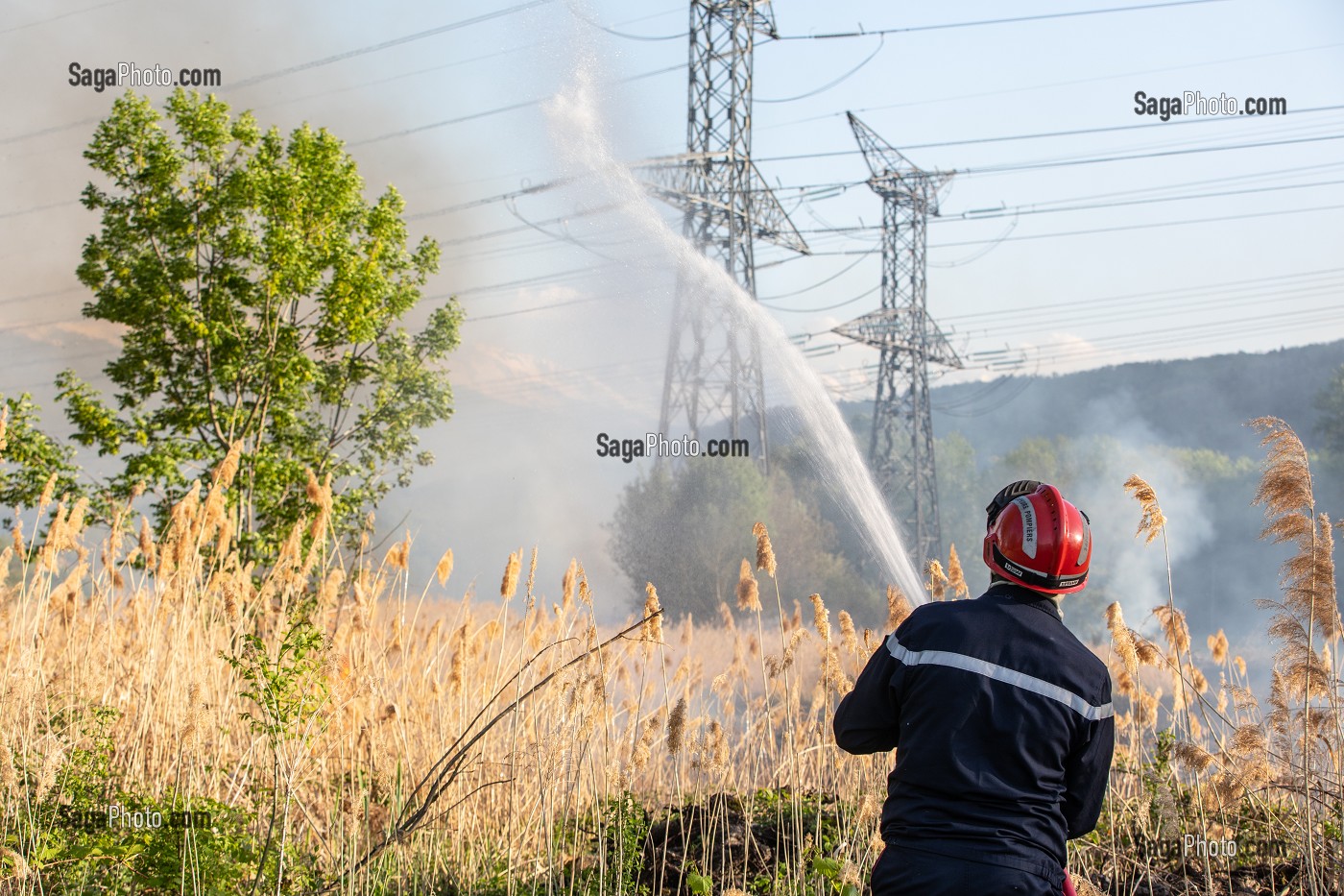 SAPEUR-POMPIER EN TRAIN D'ETEINDRE UN FEU DE BROUSSAILLES (ROSEAUX) SOUS DES PYLONES DE LIGNES A HAUTE TENSION, SAPEURS-POMPIERS PRINCIPAL DU CENTRE DE SECOURS DE CHAMBERY, LES MARCHES, SAVOIE (73), FRANCE 