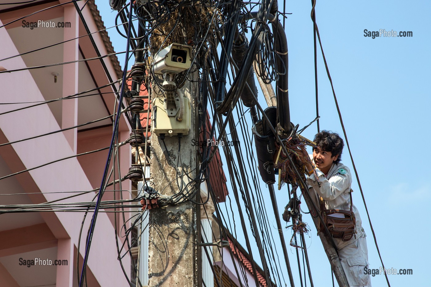 EMPLOYE AU TRAVAIL DANS L'ENCHEVETREMENT DE FILS ELECTRIQUES ET TELEPHONIQUES TYPIQUES DU RESEAU THAILANDAIS, BANG SAPHAN, THAILANDE, ASIE 