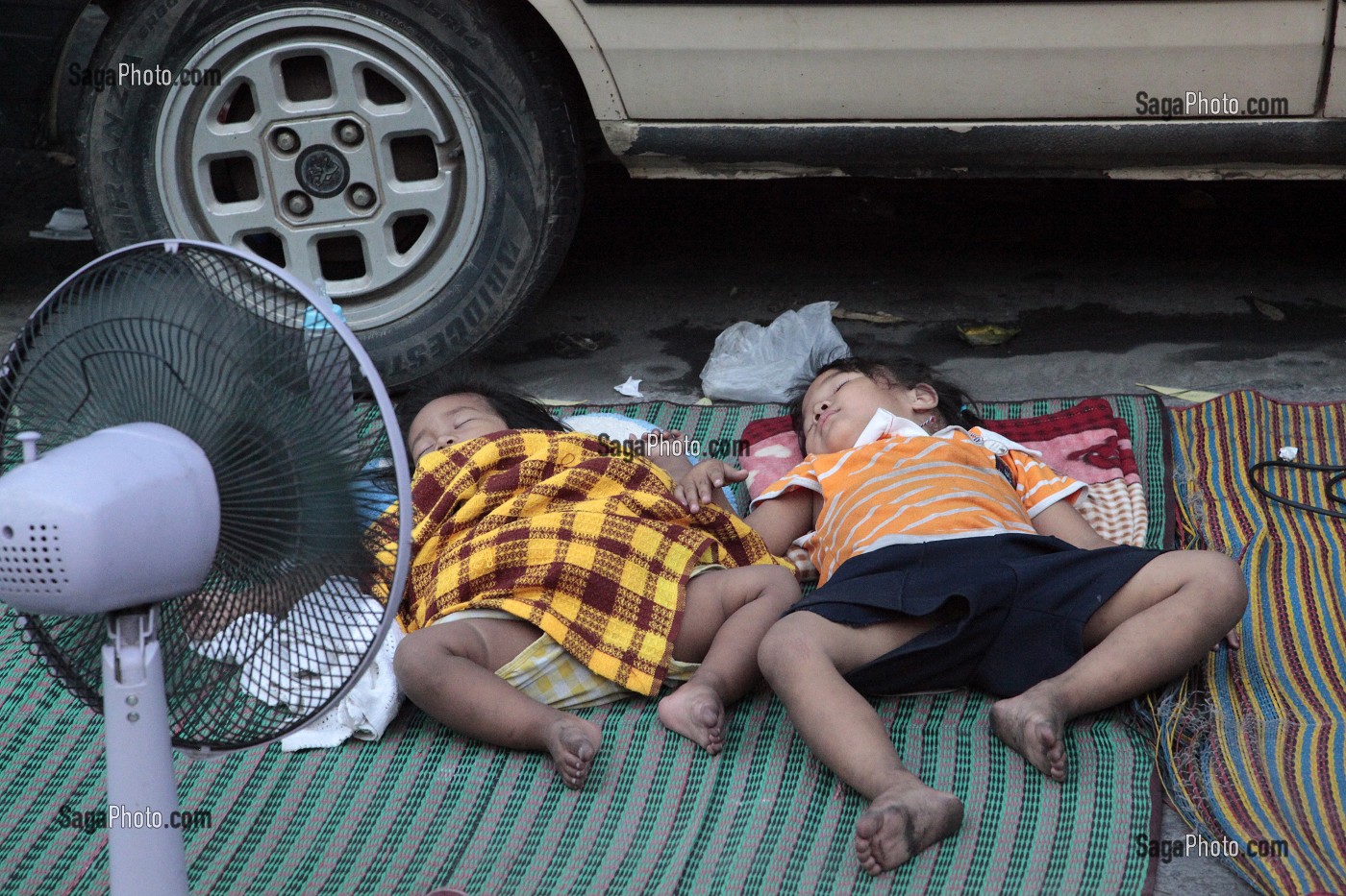 ENFANTS DORMANT PAR TERRE, PRES D'UN VENTILATEUR, DANS LA RUE, BANGKOK, THAILANDE, ASIE 