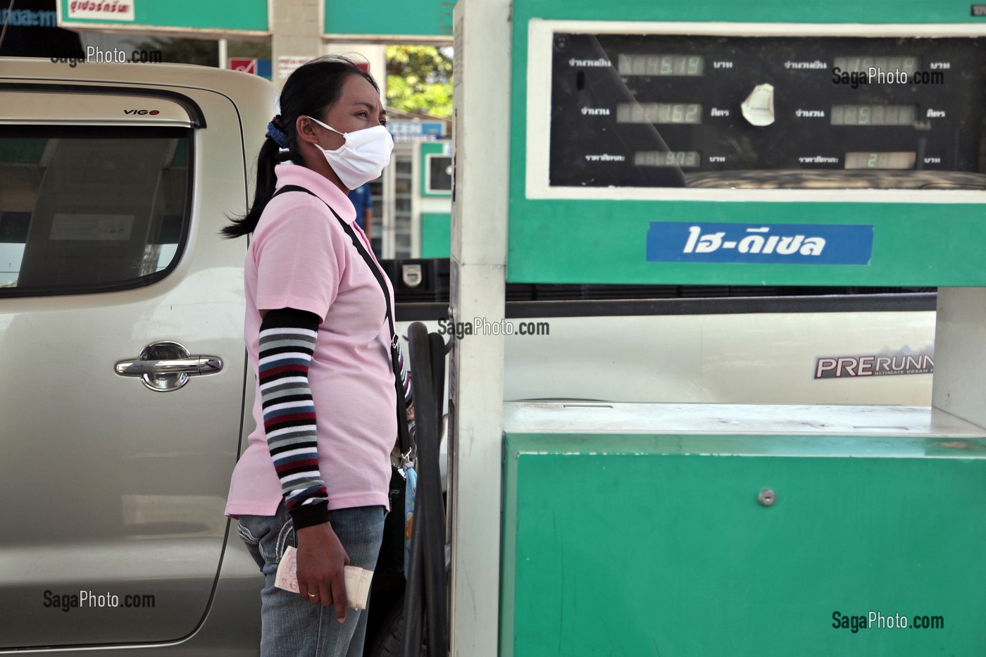 POMPISTE AVEC SON MASQUE DE PROTECTION A LA STATION SERVICE, BANG SAPHAN, THAILANDE 