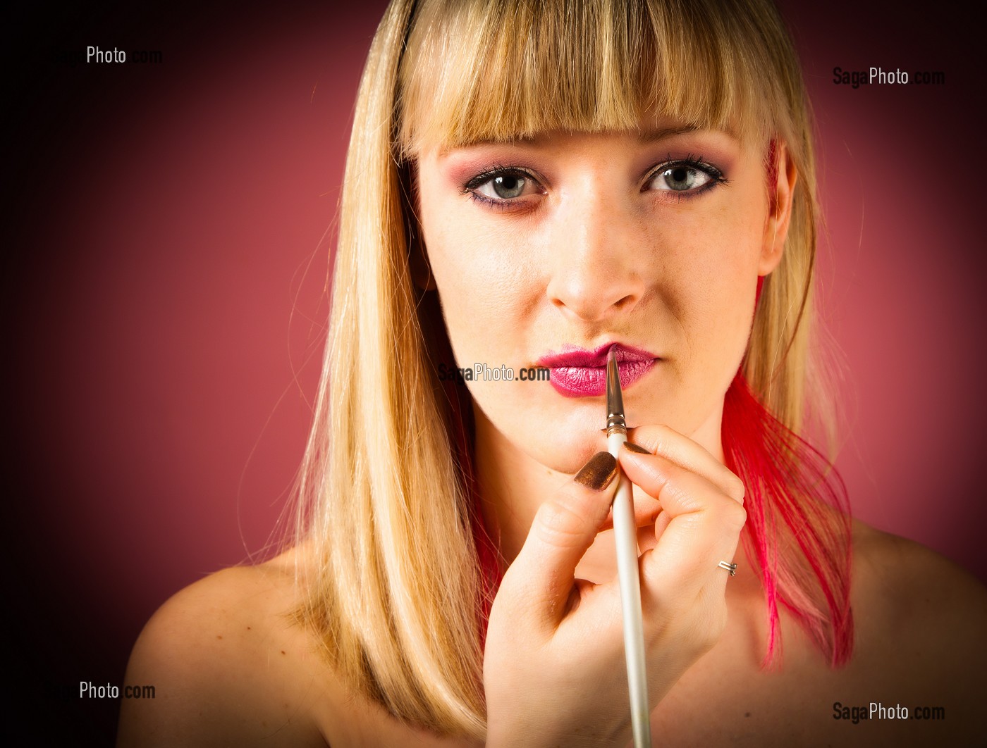 MAQUILLAGE, PORTRAIT D'UNE MAQUILLEUSE PROFESSIONNELLE S'APPLIQUANT DU ROUGE A LEVRES AVEC UN PINCEAU 