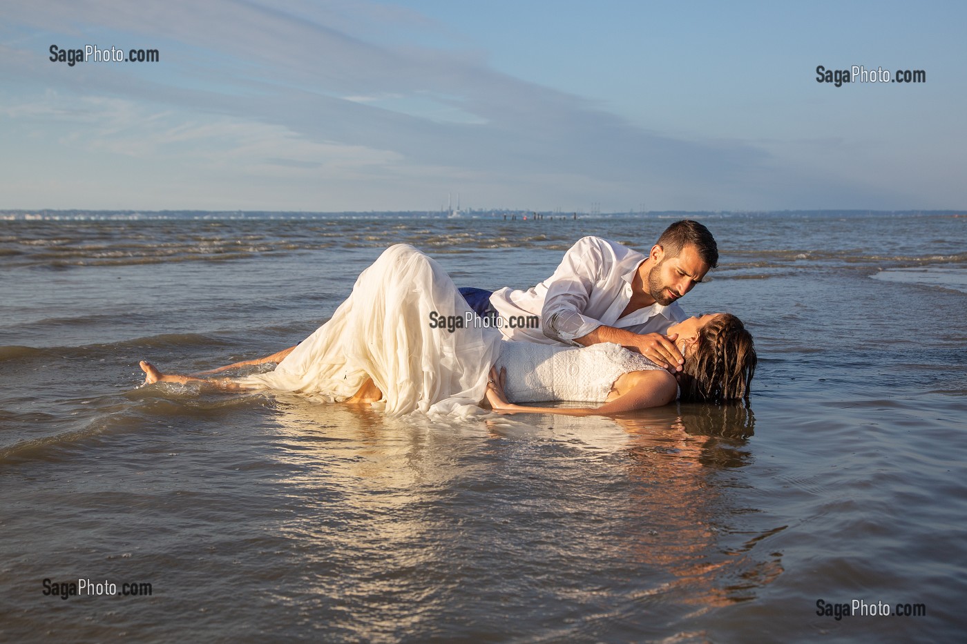 BISOUS TENDRES D'UN COUPLE DE MARIES DANS LA MER, MARIAGE TRASH THE DRESS, TROUVILLE-SUR-MER, NORMANDIE, FRANCE 