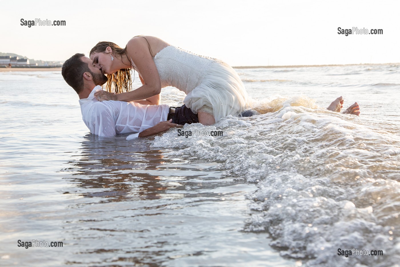 BISOUS TENDRES D'UN COUPLE DE MARIES DANS LA MER, MARIAGE TRASH THE DRESS, TROUVILLE-SUR-MER, NORMANDIE, FRANCE 