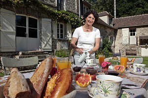 ISABELLE HEITZ QUI PREPARE LE PETIT DEJEUNER DEVANT LA FACADE EN PIERRE DE LA  CHAMBRE D'HOTES DU MOULIN DE LONCEUX, OINVILLE-SOUS-AUNEAU, EURE-ET-LOIR (28), FRANCE 