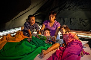 LECTURE D'UNE HISTOIRE AUX ENFANTS AU MOMENT DU COUCHER, VACANCES AU VERT EN FAMILLE AU CAMPEMENT HUTTOPIA, FORET DE SENONCHES, PERCHE, EURE-ET-LOIR (28), CENTRE, FRANCE 