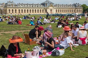 FEMMES ELEGANTES ET COIFFEES DE CHAPEAUX, ASSISTANT AU PIQUE-NIQUE CHIC DES JARDINS DE DIANE, AVEC AU FOND LES GRANDES ECURIES DU CHATEAU DE CHANTILLY, PRIX DE DIANE LONGINES 2013, HIPPODROME DE CHANTILLY, OISE (60), FRANCE 