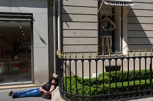 JEUNE FEMME SE REPOSANT SUR LE TROTTOIR, VITRINE DU MAGASIN DE LA MARQUE CHANEL, AVENUE MONTAIGNE, 8EME ARRONDISSEMENT, PARIS, FRANCE 