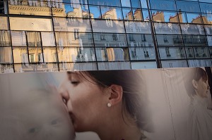 PANNEAU PUBLICITAIRE D'UNE FEMME QUI EMBRASSE SON BEBE DEVANT UN IMMEUBLE DE BUREAU MODERNE ET VITRE, QUARTIER DU MONTPARNASSE, RUE FALGUIERES, 15 EME ARRONDISSEMENT, PARIS, FRANCE 