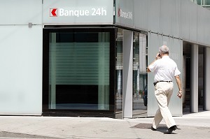 HOMME D'AFFAIRE AVEC SON TELEPHONE PORTABLE DEVANT UNE BANQUE 24H SUR 24, GENEVE, SUISSE 