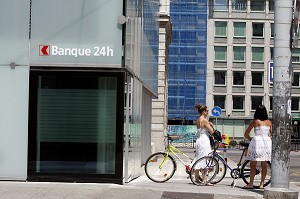 FEMMES A VELO DEVANT UNE BANQUE 24H SUR 24, GENEVE, SUISSE 