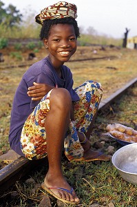 ENFANT ASSIS SUR UN RAIL, VENDANT DE LA NOURRITURE PRES DE LA GARE A LA FRONTIERE ENTRE LA COTE D'IVOIRE ET LE BURKINA FASO 