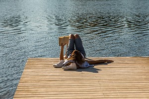 JEUNE FEMME LISANT UN LIVRE SUR UN PONTON EN BOIS AU BORD DE L'ALLIER, DETENTE, LOISIRS, LIBERTE, SILENCE, VICHY, ALLIER, REGION AUVERGNE-RHONE-ALPES, FRANCE 