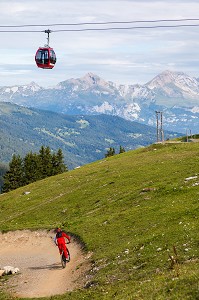 AMATEUR DE VTT DESCENDANT UNE PISTE DE VTT DANS LA STATION DE LENZERHEIDE AVEC LES TELECABINES ET LES ALPES SUISSES EN FOND, LENZERHEIDE, CANTON DES GRISONS, SUISSE 