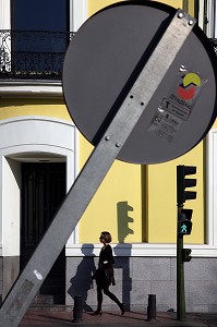 FEMME QUI MARCHE DANS LA RUE SOUS UN PANNEAU PENCHE, PASEO DE RECOLETOS, MADRID, ESPAGNE 