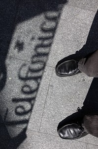 PIEDS ET CHAUSSURES DEVANT L'OMBRE D'UNE CABINE TELEPHONIQUE (TELEFONICA), QUARTIER LATINA, MADRID, ESPAGNE 