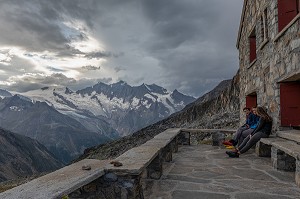 RANDONNEURS SUR LA TERRASSE D'UN REFUGE PAR TEMPS D'ORAGE, ALMAGELLERHUTTE, WEISSMIES, SAAS ALMAGELL, VALAIS, SUISSE 