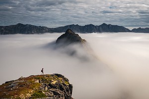 RANDONNEUSE AU SOMMET DU MONT HESTEN CONTEMPLANT DES PICS EMERGEANT D'UNE MER DE NUAGES, FJORDGARD, SENJA, NORVEGE 