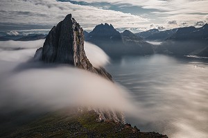 MONT SEGLA ENTOURE DE NUAGES SE JETANT DANS LE FJORD, FJORDGARD, SENJA, NORVEGE 