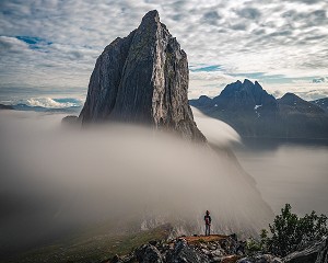 RANDONNEUSE AU PIED DU MONT SEGLA ENTOURE DE NUAGES SE JETANT DANS LE FJORD, FJORDGARD, SENJA, NORVEGE 