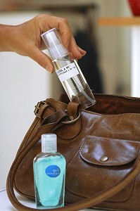 FEMME RANGEANT DES FLACONS DE LOTION DESINFECTANTE ET D'ALCOOL A 90 DEGRES DANS SON SAC A MAIN, GESTES DE PREVENTION ET DE LUTTE CONTRE LE VIRUS H1N1 OU LA GRIPPE A 