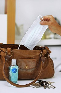 FEMME RANGEANT UN FLACON DE LOTION DESINFECTANTE ET UN MASQUE CHIRURGICAL DANS SON SAC A MAIN, GESTES DE PREVENTION ET DE LUTTE CONTRE LE VIRUS H1N1 OU LA GRIPPE A 