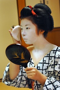 MAQUILLAGE TRADITIONNEL (DORAN) D’UNE MAIKO (APPRENTIE GEISHA), APPLICATION SUR LE VISAGE DE POUDRE DE RIZ AVEC UNE EPONGE (KONYAKU) SUR LE FARD BLANC (SHIRONURI), LA MAIKO A UN CHIGNON EN FORME DE PECHE FENDUE (WARESHINOBU) ORNE DE RUBANS ROUGES EN SOIE (KANOKO) ET PORTE UN KIMONO DE COTON (YUKATA), QUARTIER DE GION, KYOTO, JAPON, ASIE 