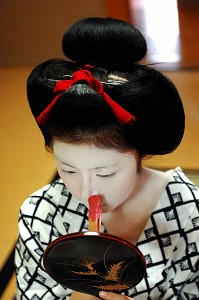 MAQUILLAGE TRADITIONNEL (DORAN) D’UNE MAIKO (APPRENTIE GEISHA), APPLICATION SUR LE VISAGE DU FARD ROSE POUR MODELER LES TRAITS AVEC UN PINCEAU DE BAMBOU (BURASHI), LA COIFFURE DE LA MAIKO EST UN CHIGNON EN FORME DE PECHE FENDUE (WARESHINOBU) ORNE DE RUBANS EN SOIE (KANOKO), QUARTIER DE GION, KYOTO, JAPON, ASIE 