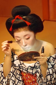 MAQUILLAGE TRADITIONNEL (DORAN) D’UNE MAIKO (APPRENTIE GEISHA), APPLICATION DU MASCARA, LA COIFFURE DE LA MAIKO EST UN CHIGNON EN FORME DE PECHE FENDUE (WARESHINOBU) ORNE DE RUBANS EN SOIE (KANOKO), QUARTIER DE GION, KYOTO, JAPON, ASIE 